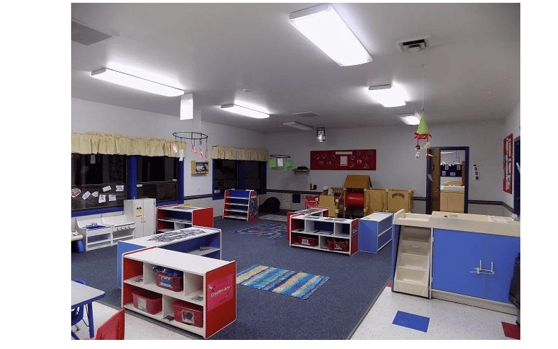 Empty colorful classroom with shelves, rugs, and play furniture