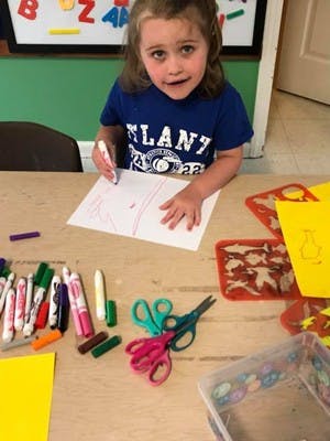 Child drawing on paper with a marker at a table
