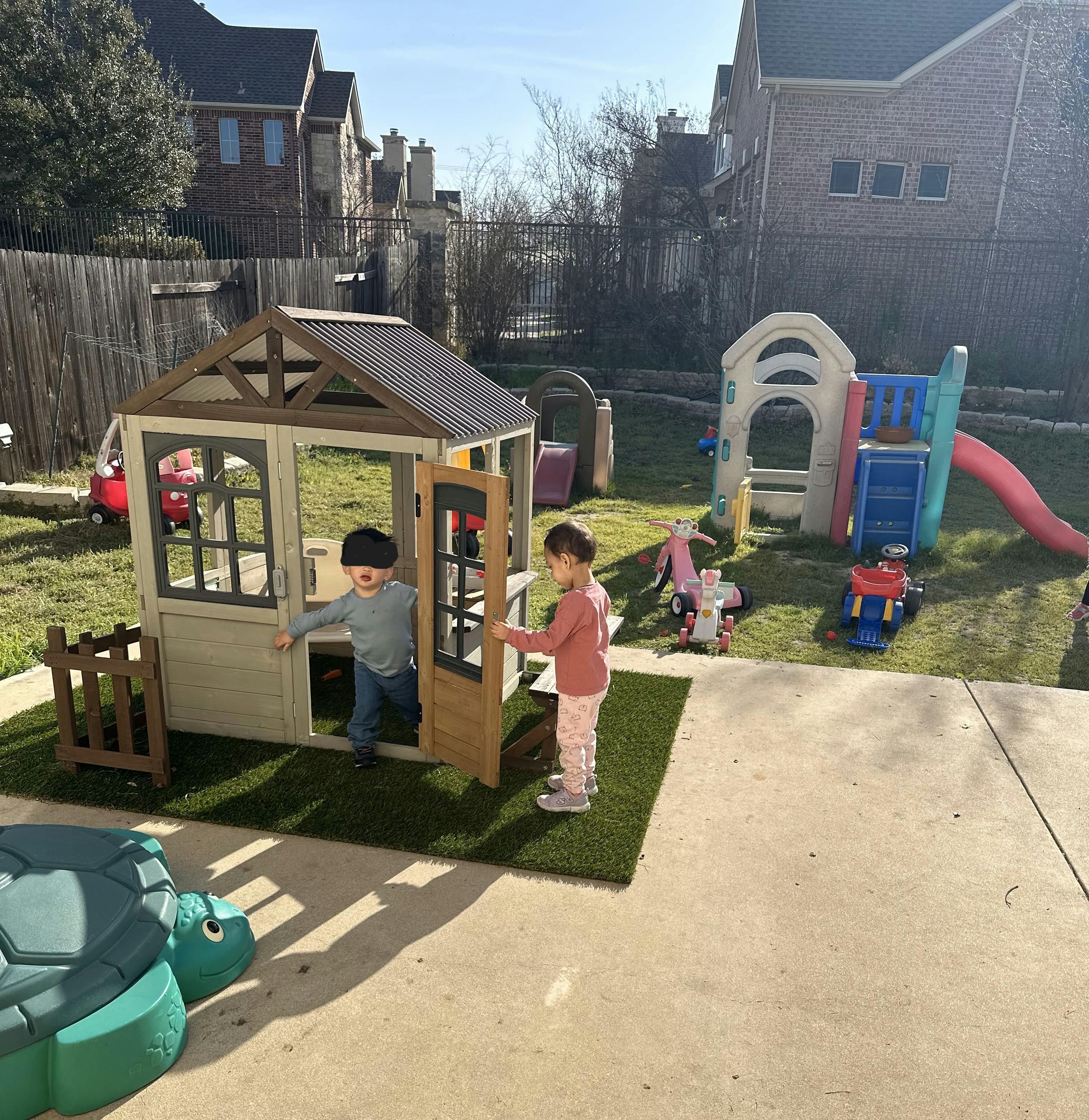Two children playing in a backyard playhouse
