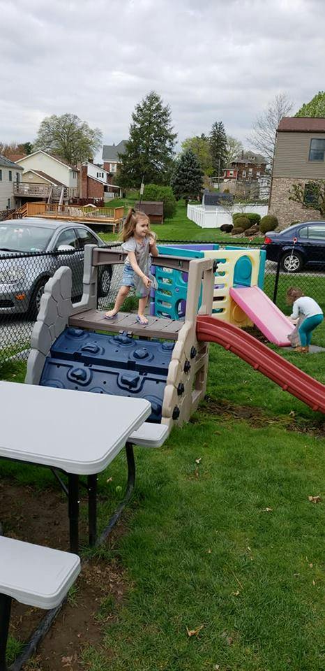 Child standing on a playground structure, another child near a slide