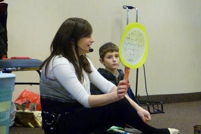 Person with headset holding a yellow paddle, child sitting nearby