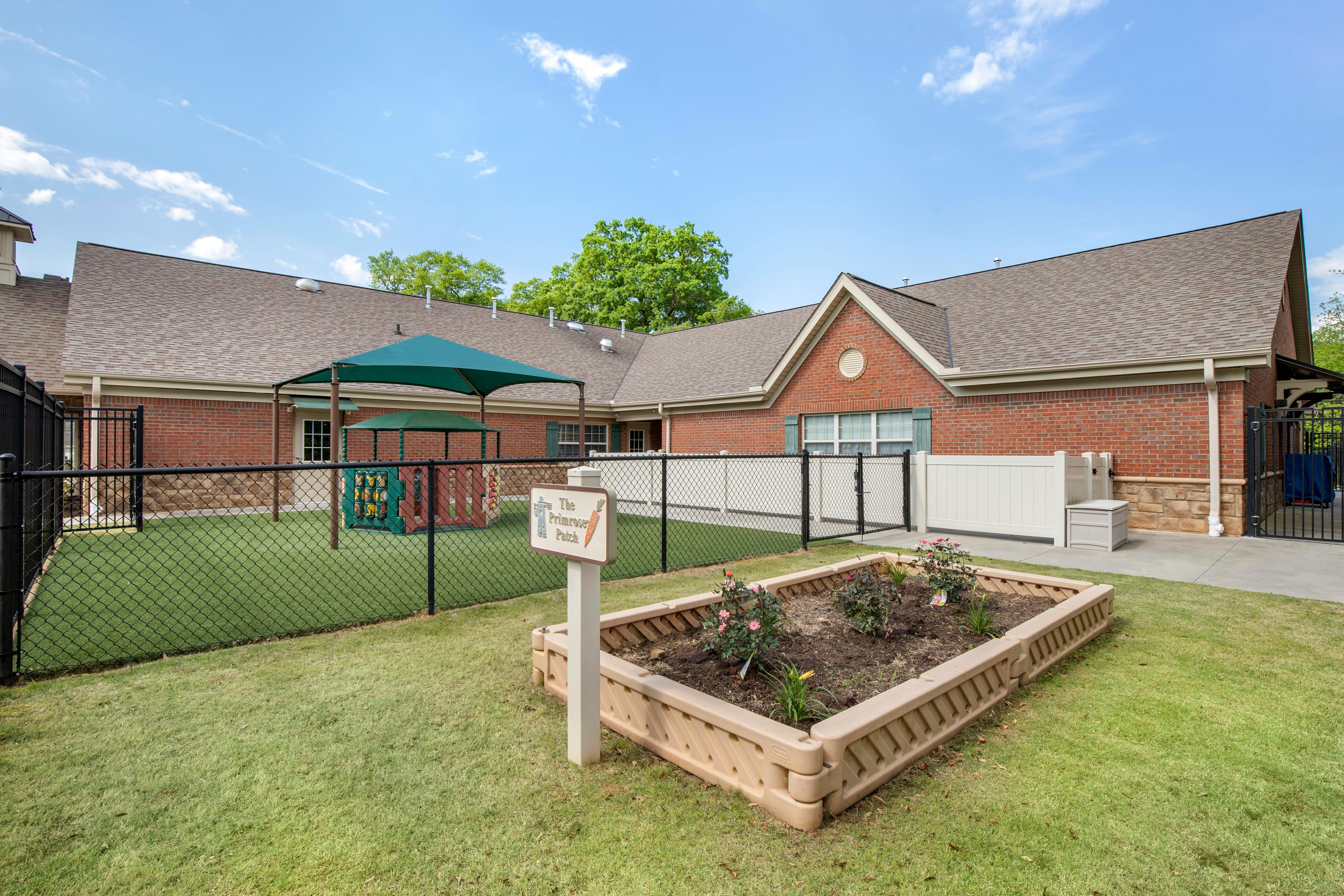 An outdoor play area with artificial grass and a red brick building