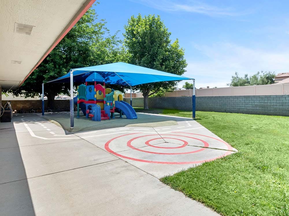 Colorful playground structure with slides under a blue shade canopy