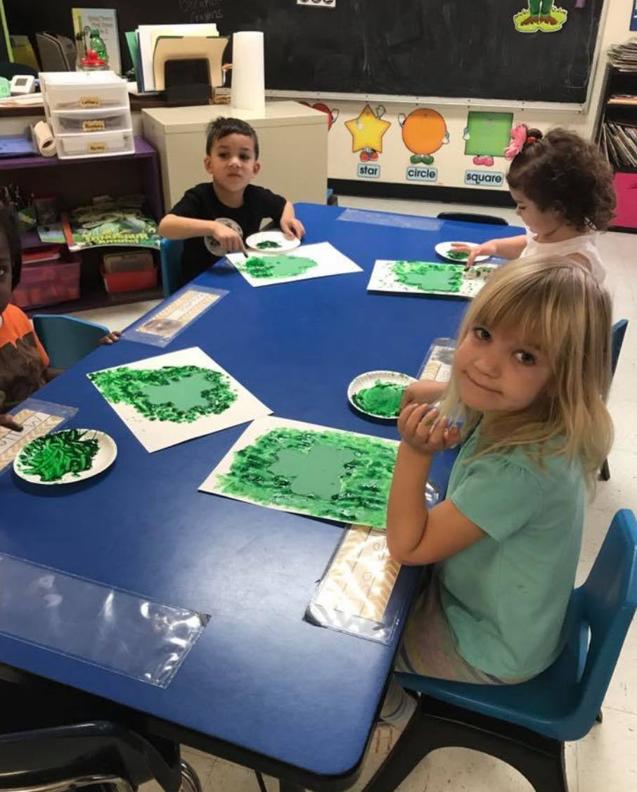 Children painting at a table in a classroom