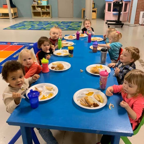 Children eating at a blue table in a classroom