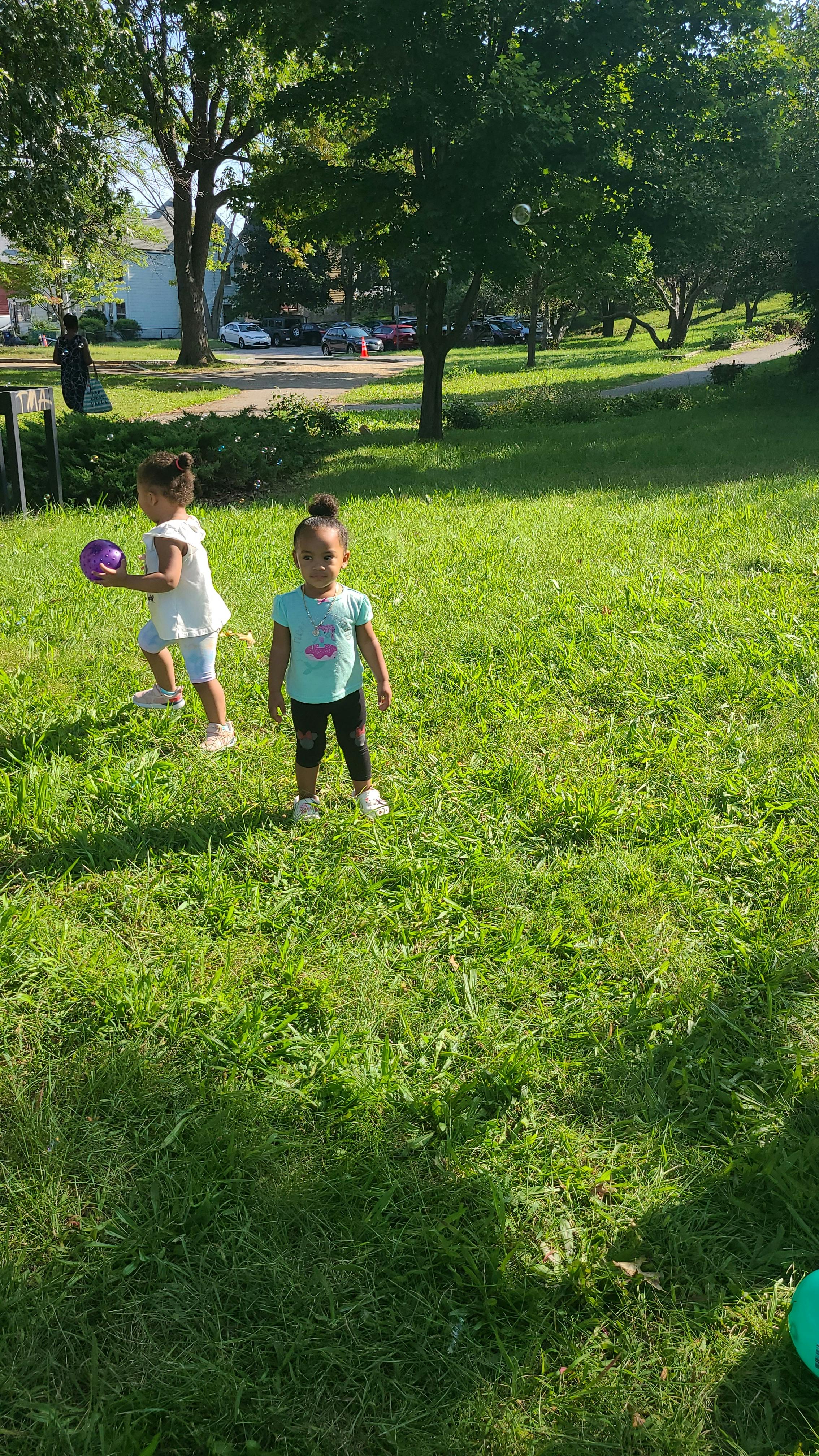 Two children playing with a purple ball in a grassy area