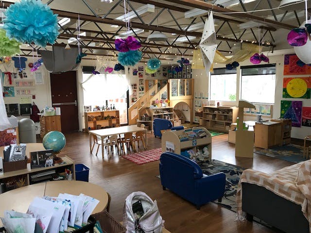 Classroom with tables, chairs, and decorations hanging from the ceiling