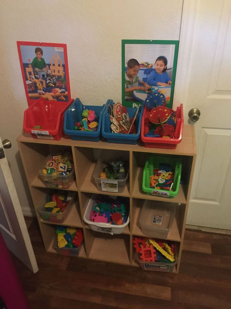 Wooden shelving unit with various toys in bins and containers