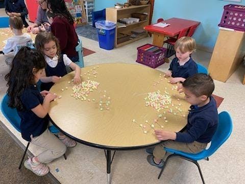 Children sitting around a table with small objects scattered on it