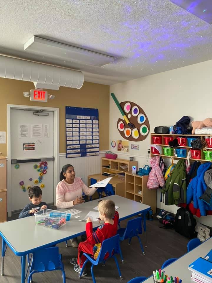 Person and two children at a table in a classroom