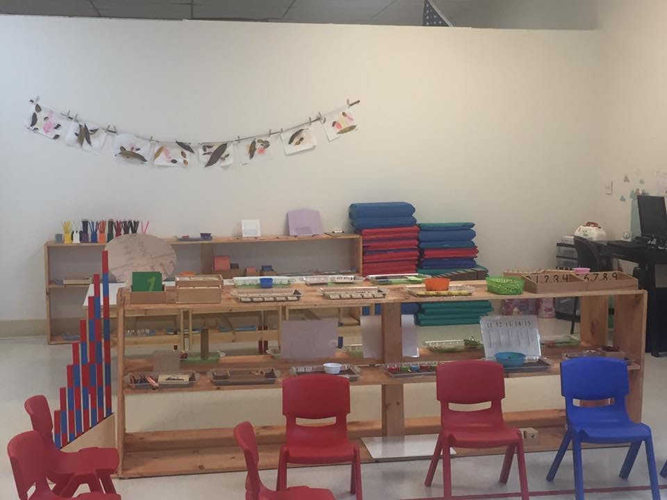Classroom with wooden shelves, learning materials, and small chairs