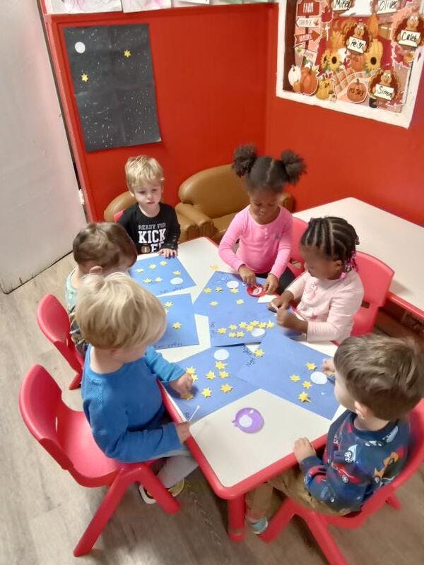 Children sitting around a table doing crafts with crafts