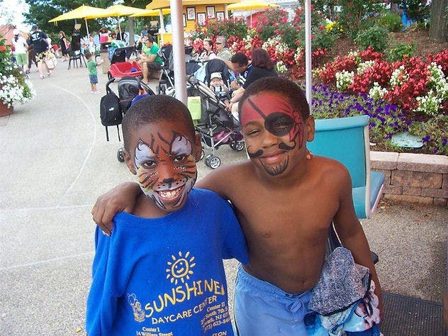 Two children with face paint, one as a tiger and one as a pirate