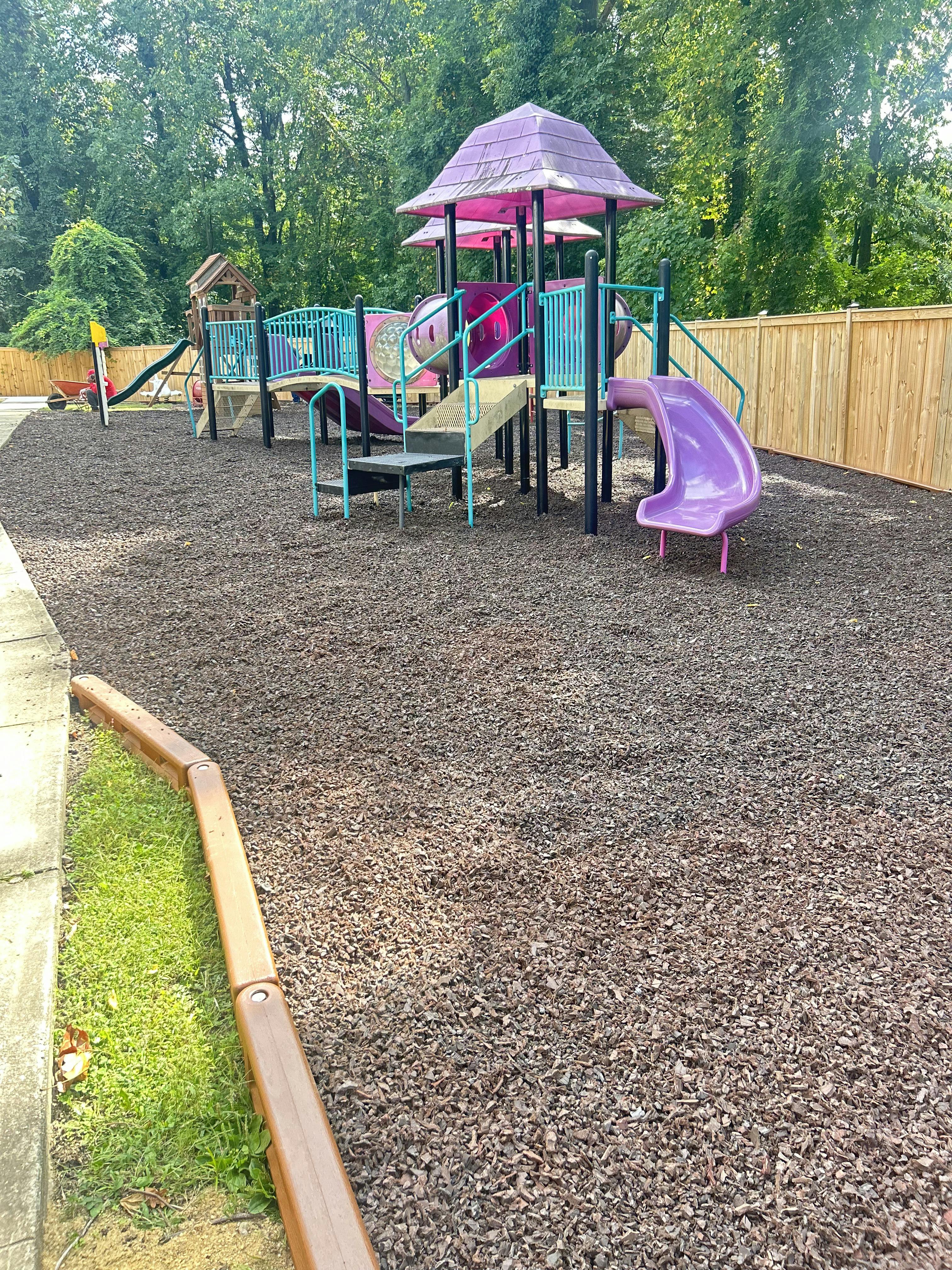 A colorful playground with slides and climbing structures on wood chips