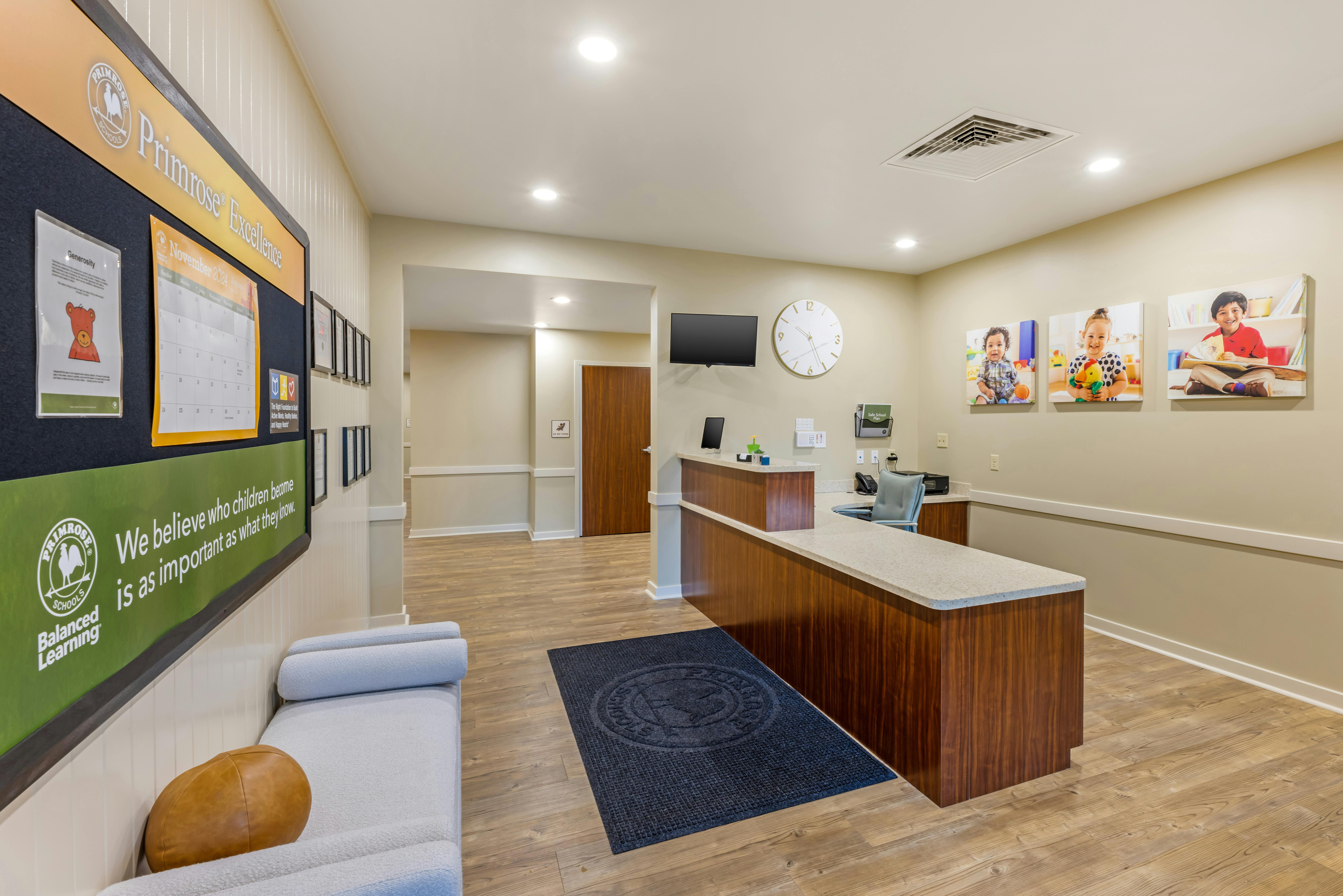 Reception area with a wooden desk, a bulletin board, and a wall with photos of children