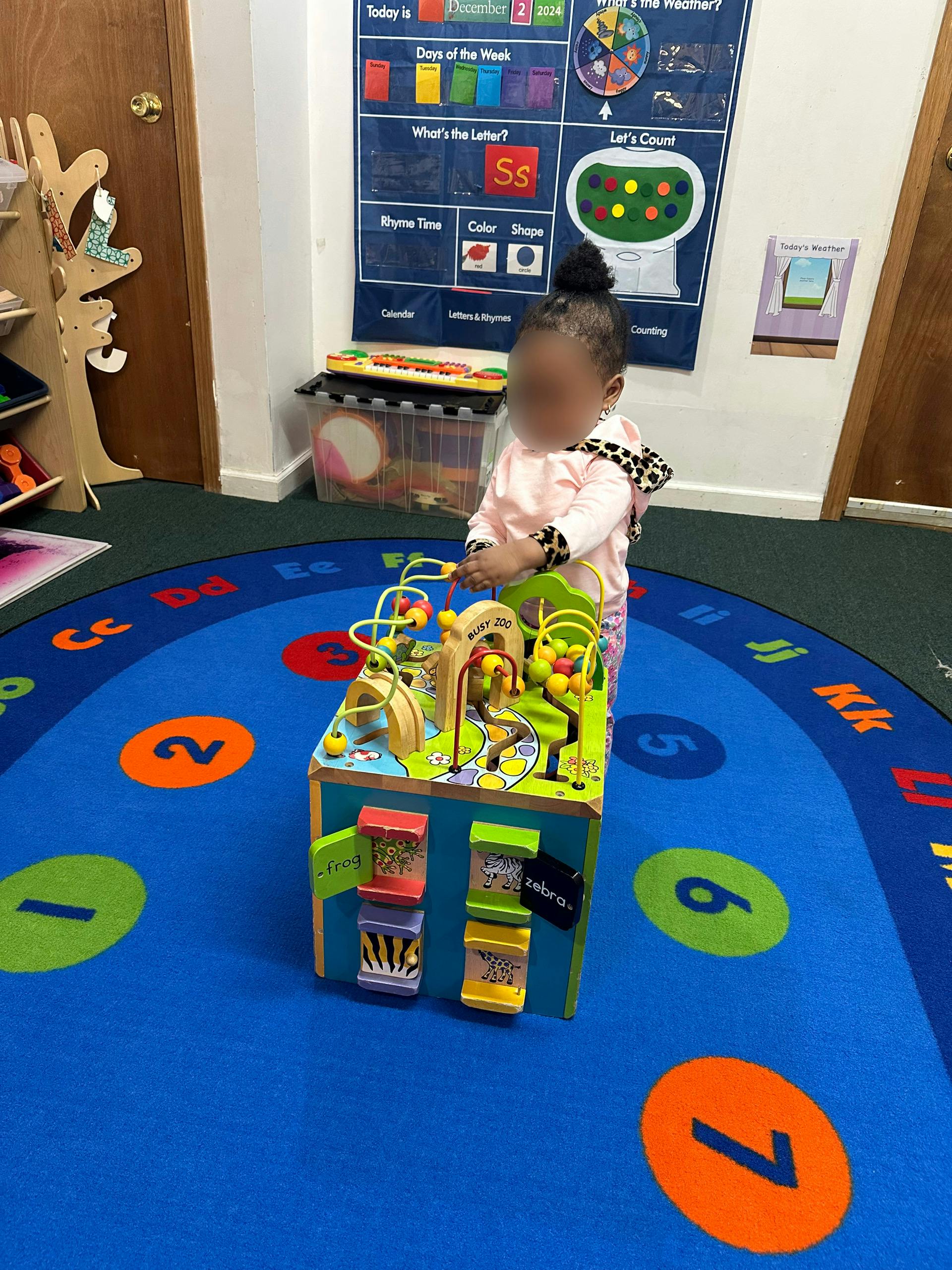 Child playing with a wooden activity cube in a classroom