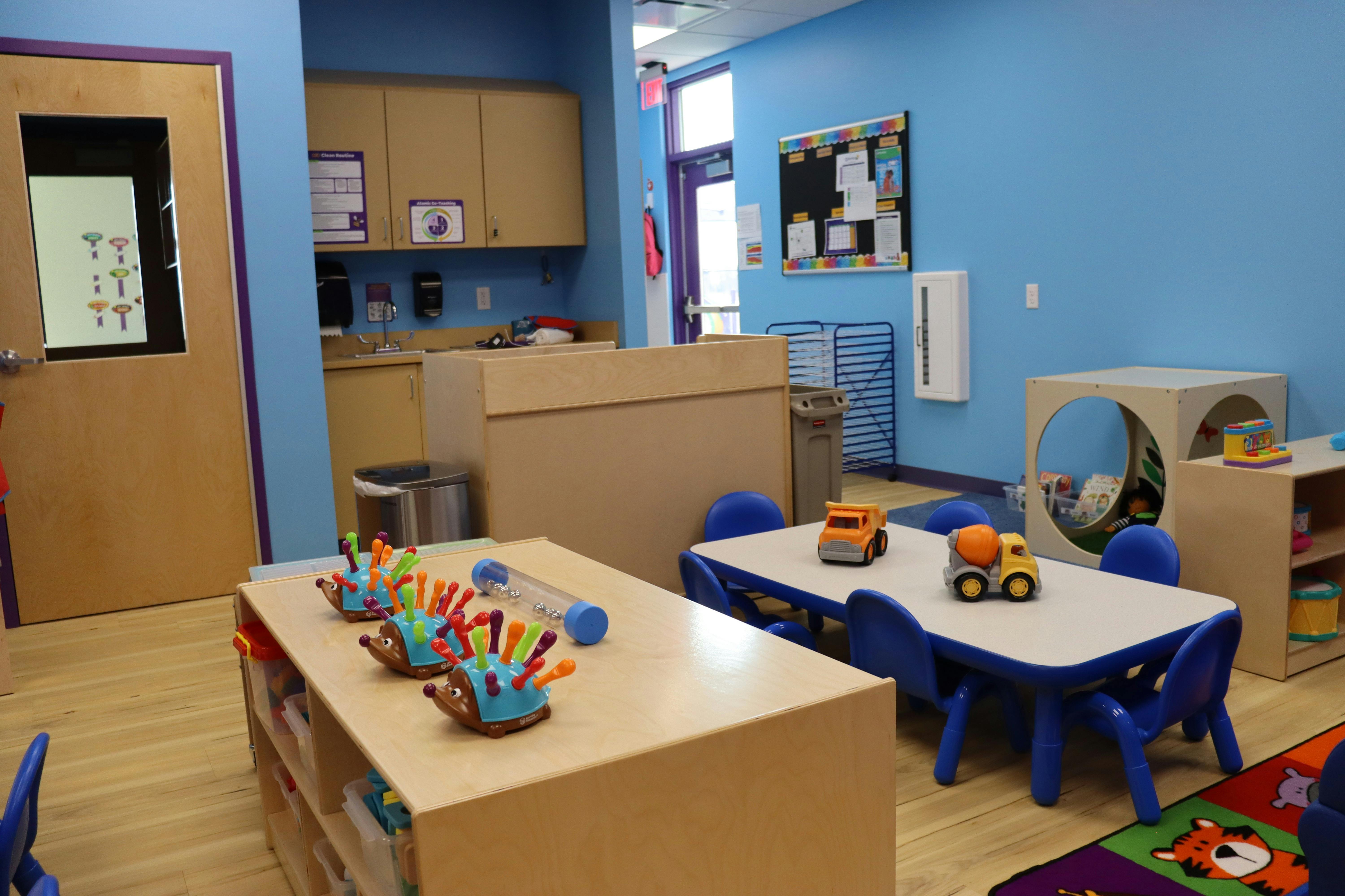 Classroom with hedgehog toys, tables, chairs, and construction trucks