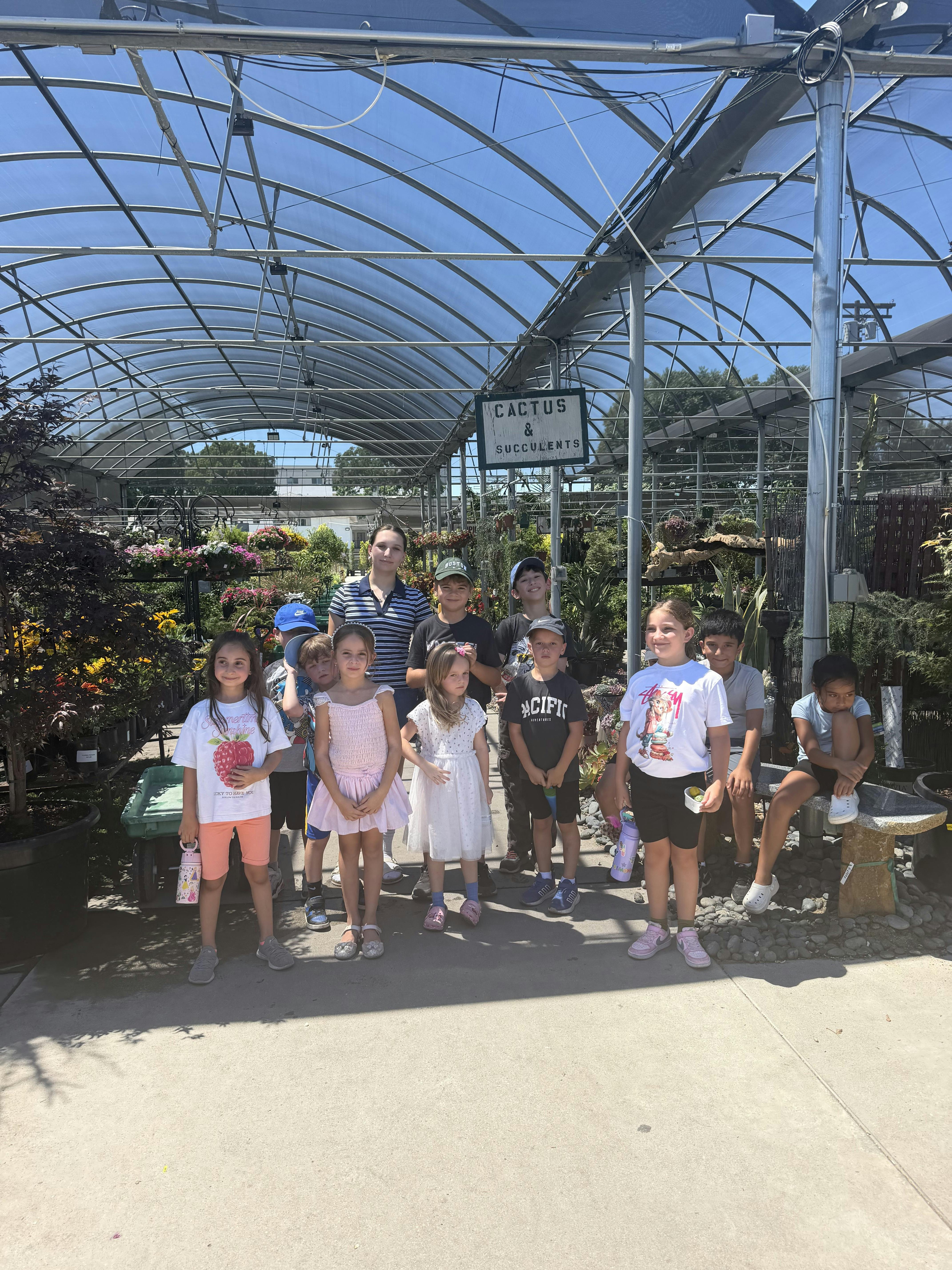 Group of children standing in a greenhouse with a Cactus and Succulents sign