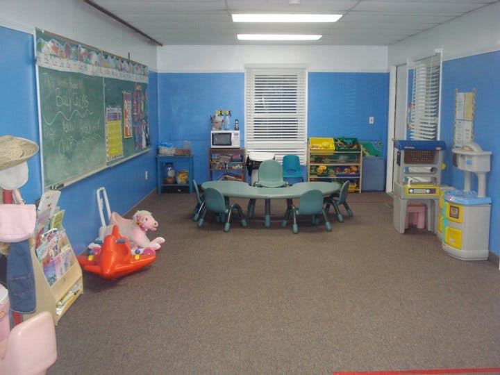 Classroom with small table and chairs, chalkboard, and toys