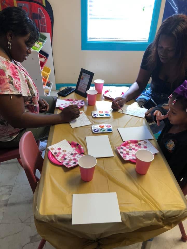 Three people painting at a table with watercolors