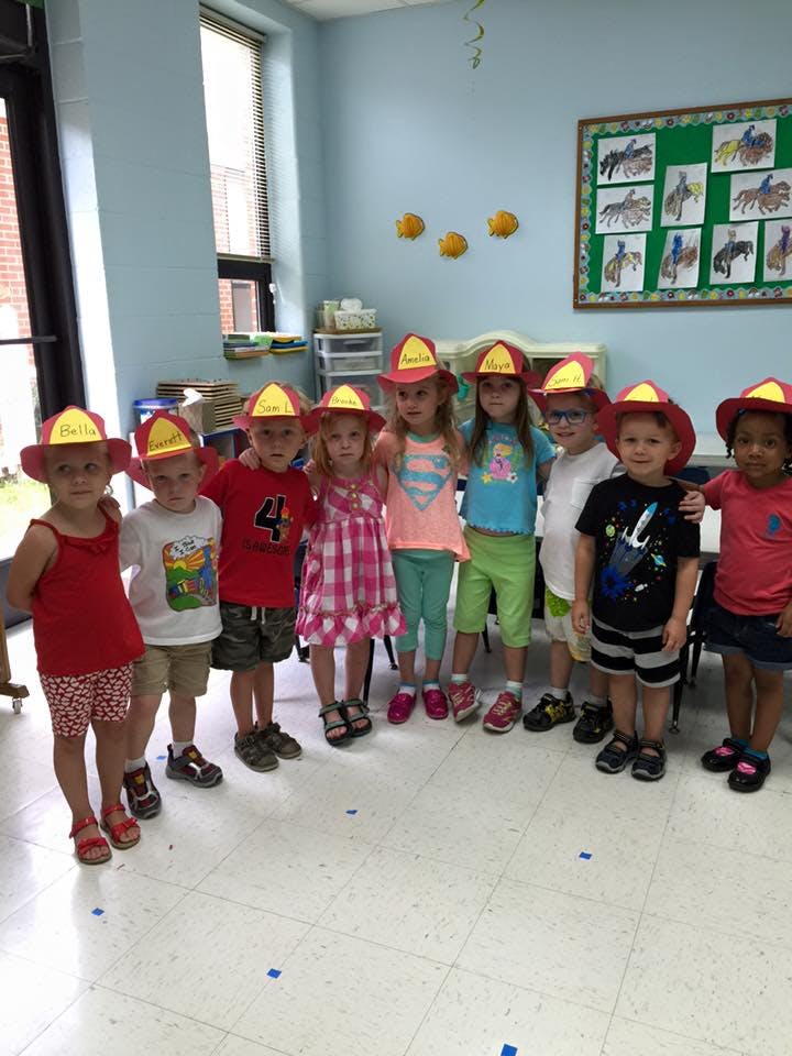 Group of children wearing firefighter hats in a classroom