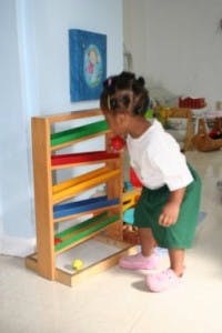 Child playing with a wooden ball run toy