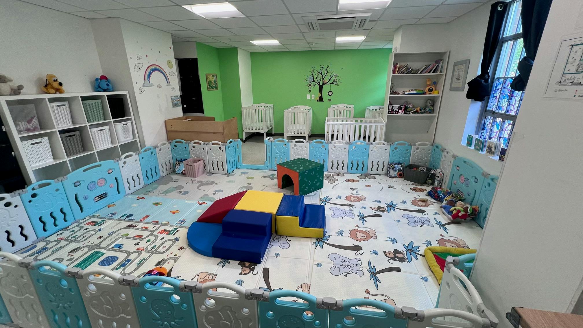 Play area for children with soft play blocks and enclosed fencing in a room