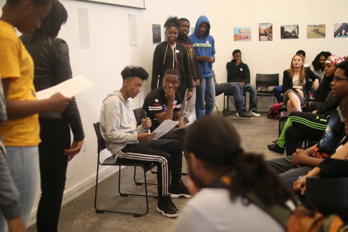 Group of teens and young adults in a room, some standing, some seated