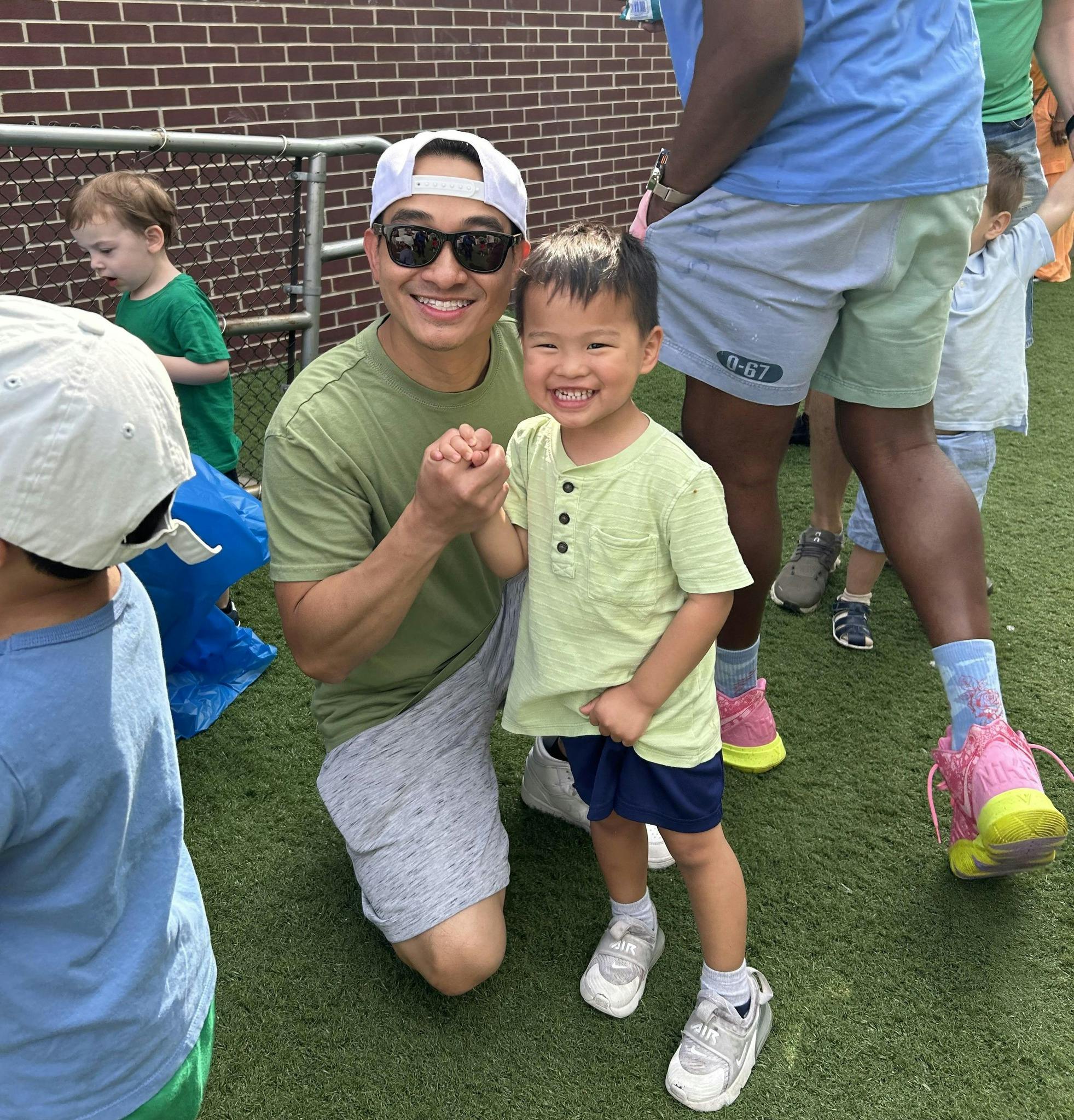 Person kneeling next to a child on grass