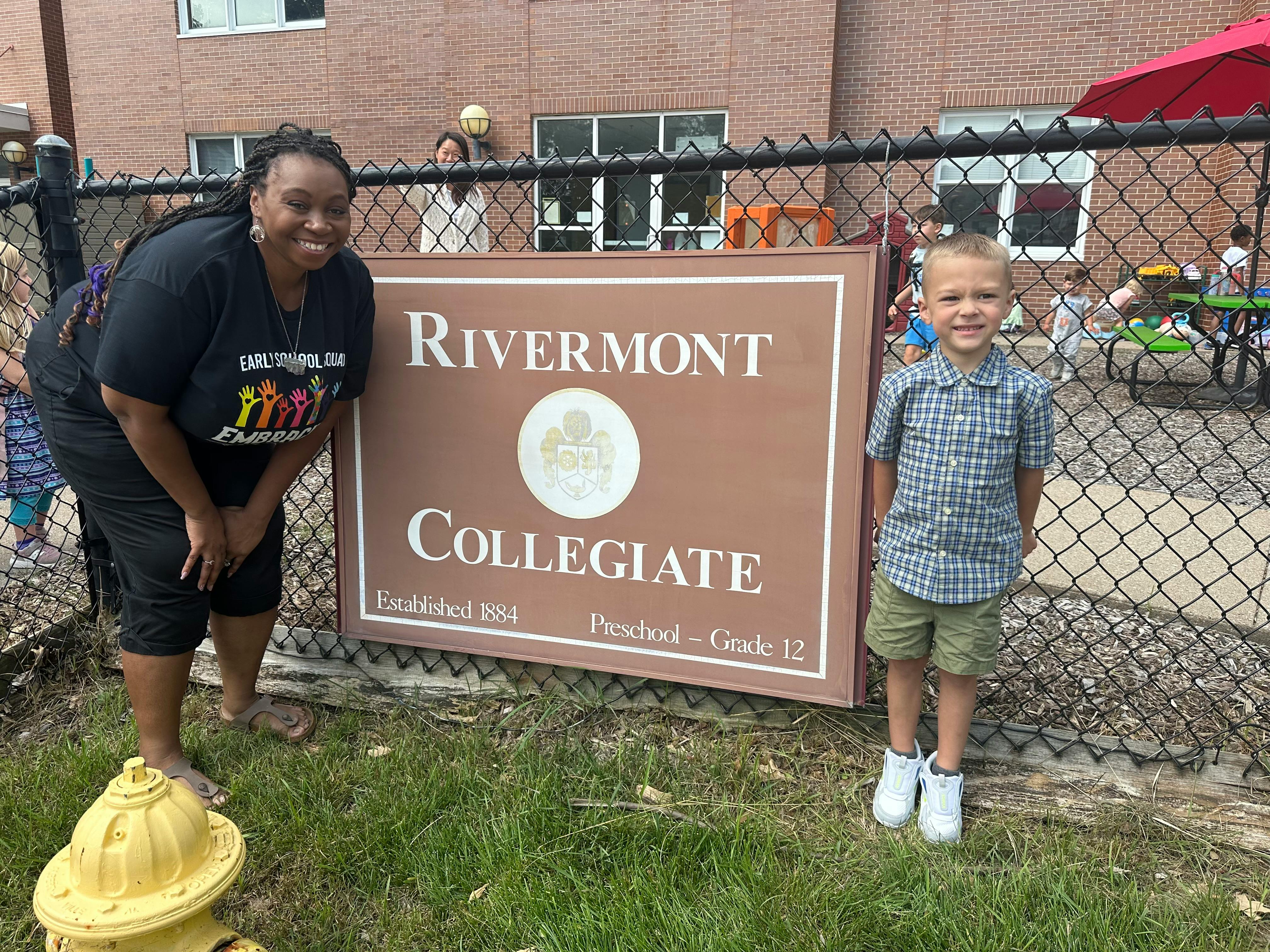 Person and child standing next to a sign for Rivermont Collegiate