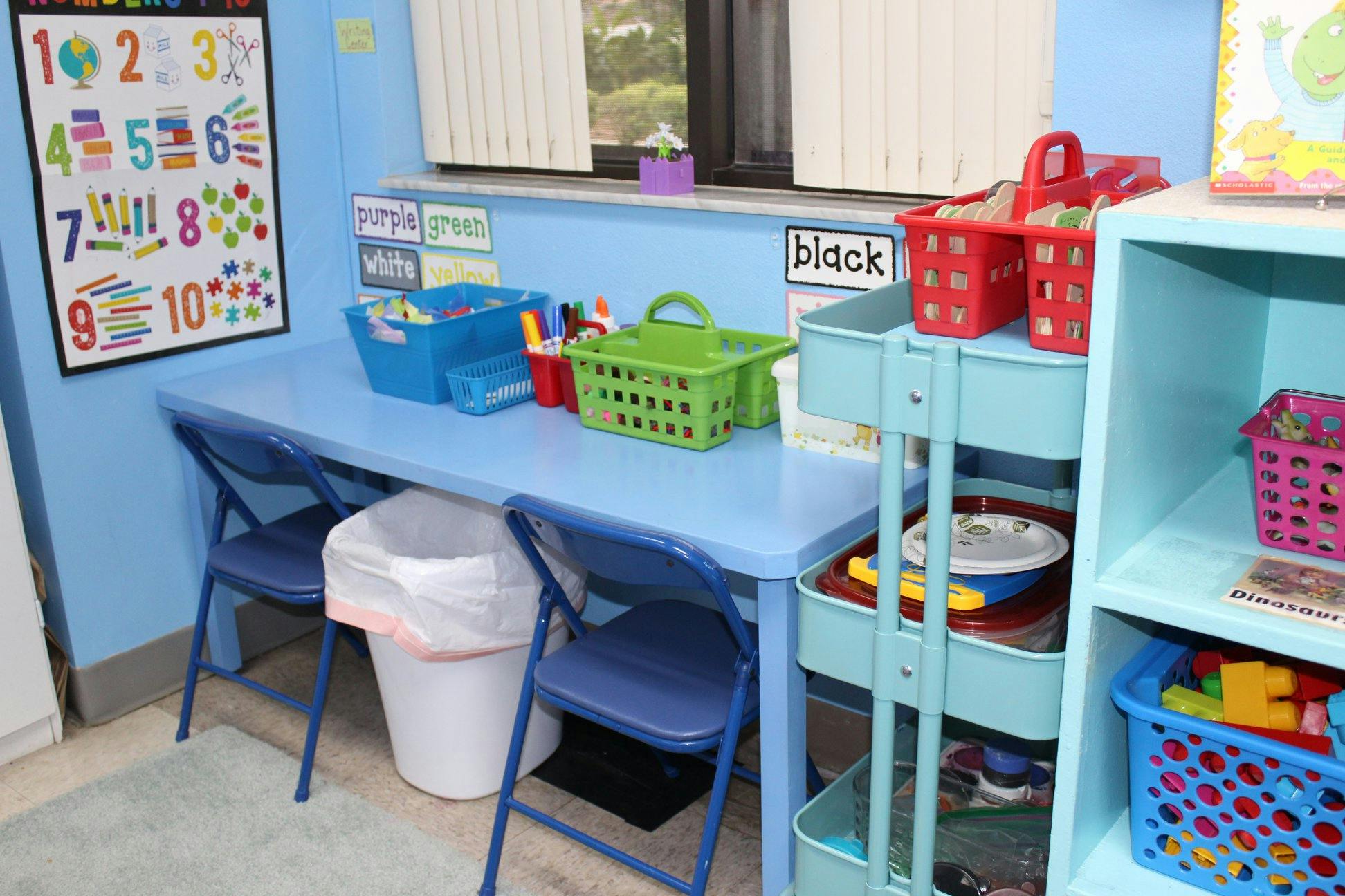 Classroom with a blue table, chairs, and storage bins