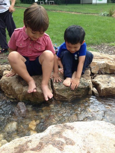 Two children sitting on rocks with their feet in water