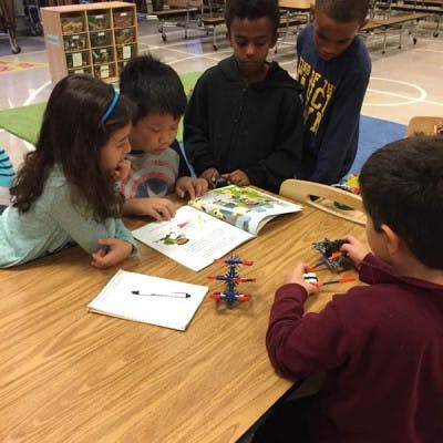 Children reading a book and playing with building toys at a table