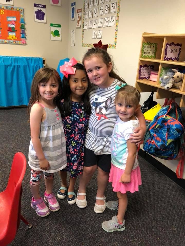 Four children standing together in a classroom