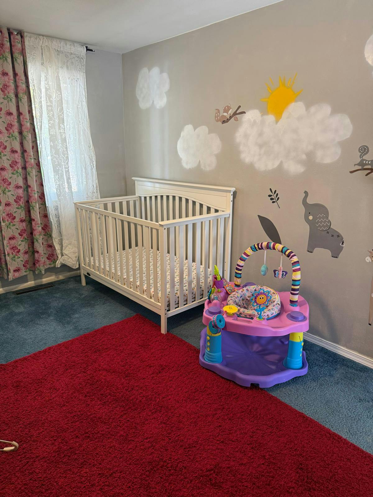 Baby crib and activity center in a room with wall decals