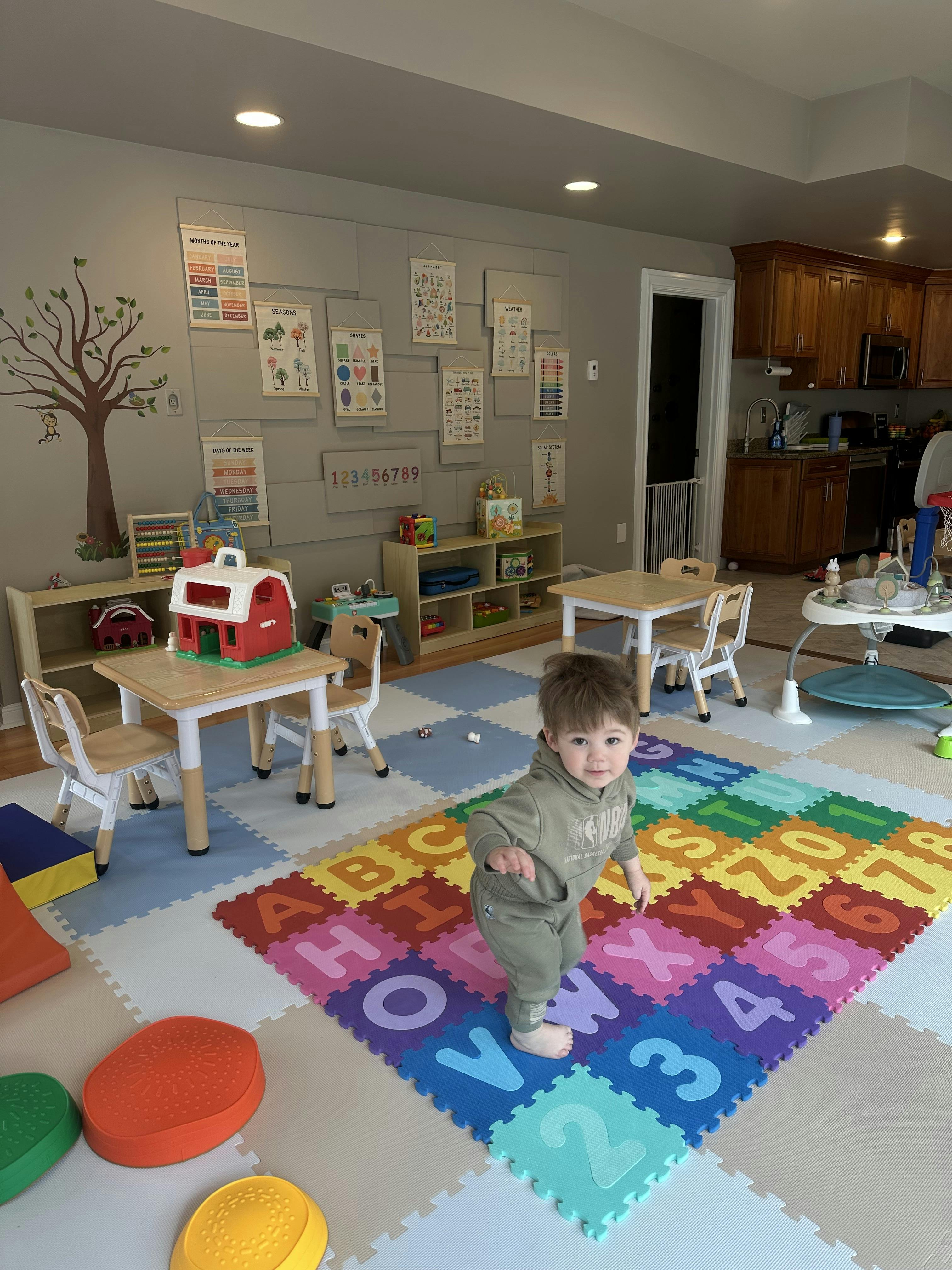 Toddler on all fours on alphabet playmat in a room with educational posters