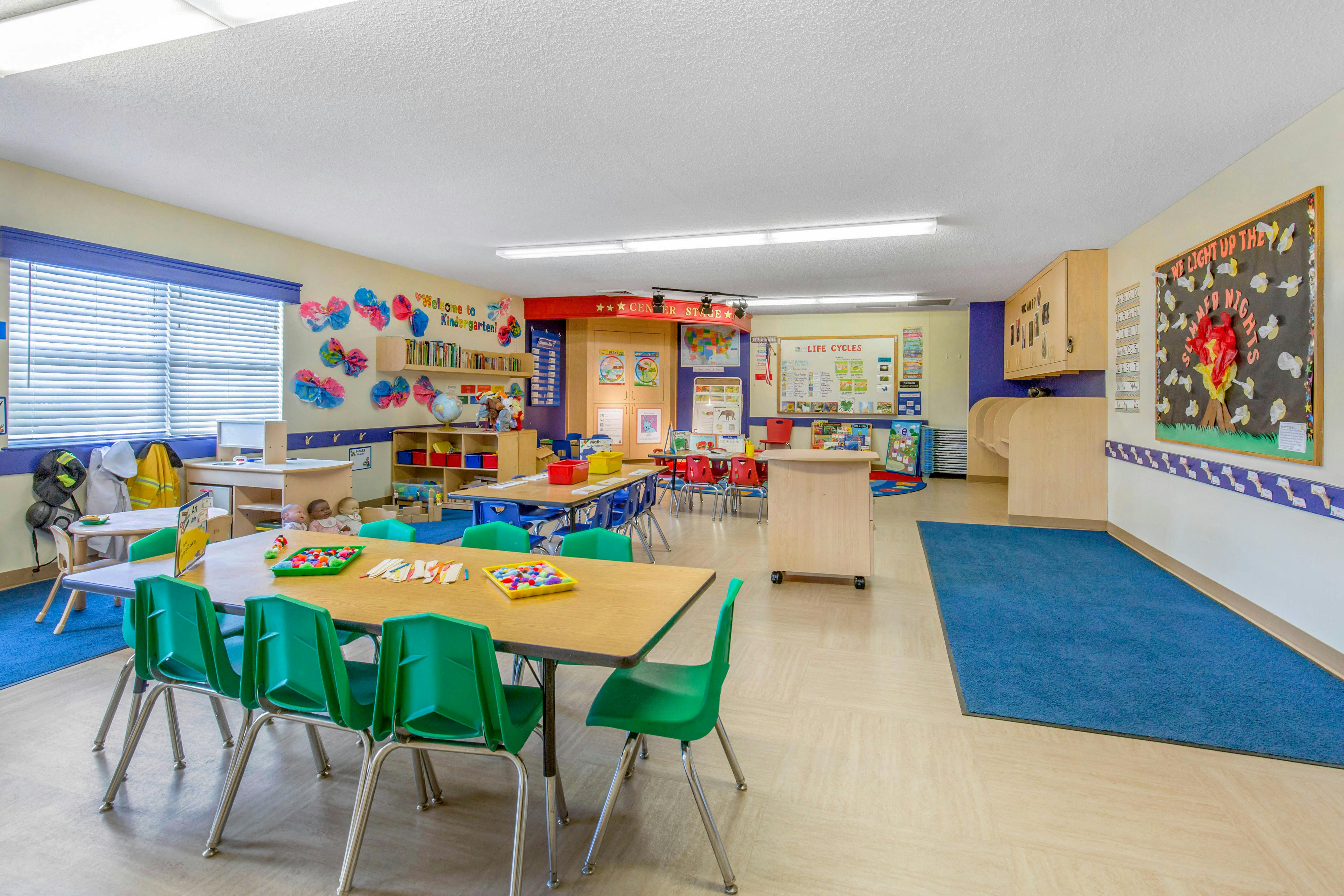 An empty kindergarten classroom with tables, chairs, and colorful decorations