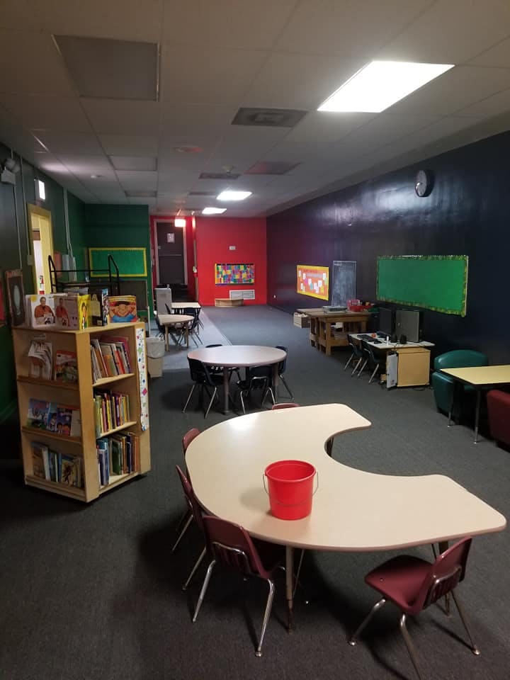 Classroom with tables, chairs, and a bookshelf