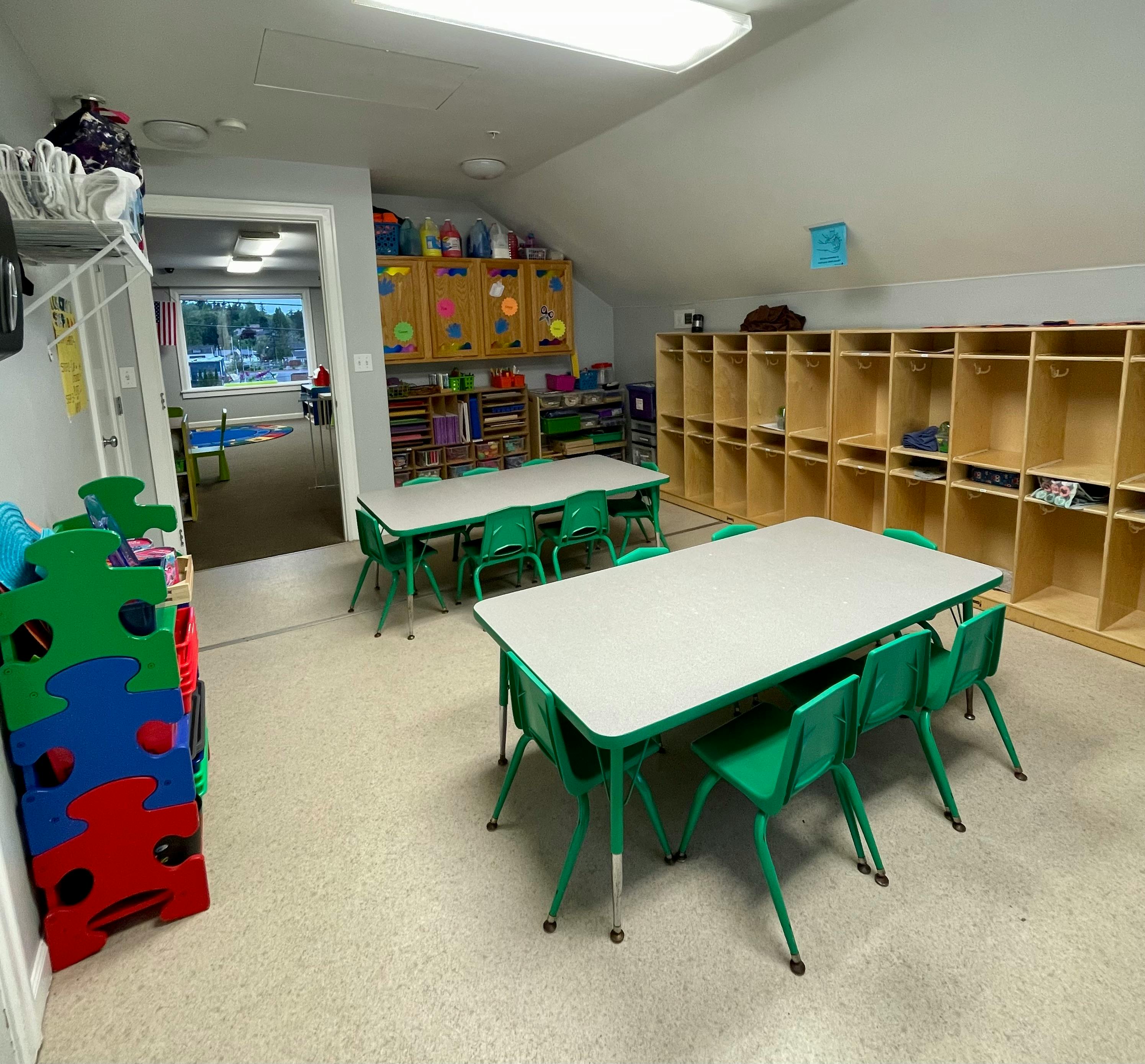 Classroom with small tables and chairs, cubbies, and storage shelves