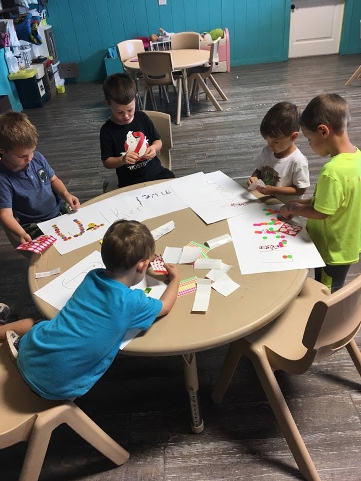 Four children sitting around a table doing crafts in-class activities