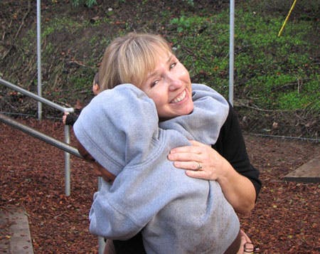 Person hugging a child wearing a hooded sweatshirt