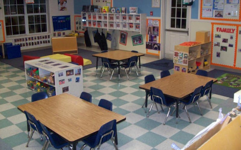 Classroom with small tables and chairs, shelves, and educational decorations
