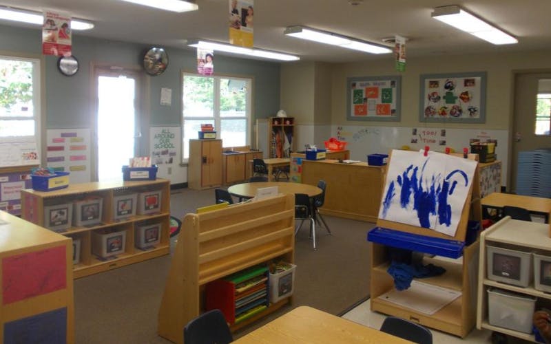 An empty early childhood classroom with activity centers and tables