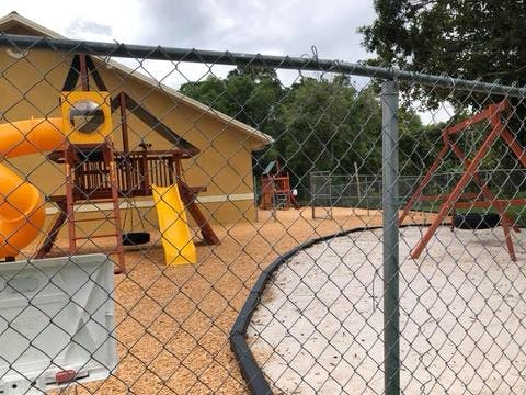 Playground with slides and swings behind a chain link fence