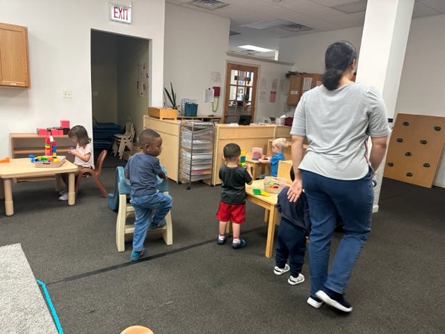 Adult supervising children playing with blocks in a classroom