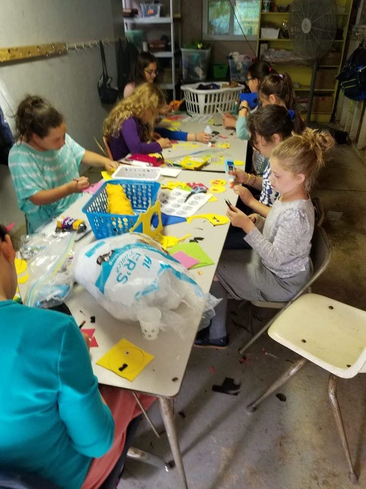 Children and teens sitting at a table doing crafts