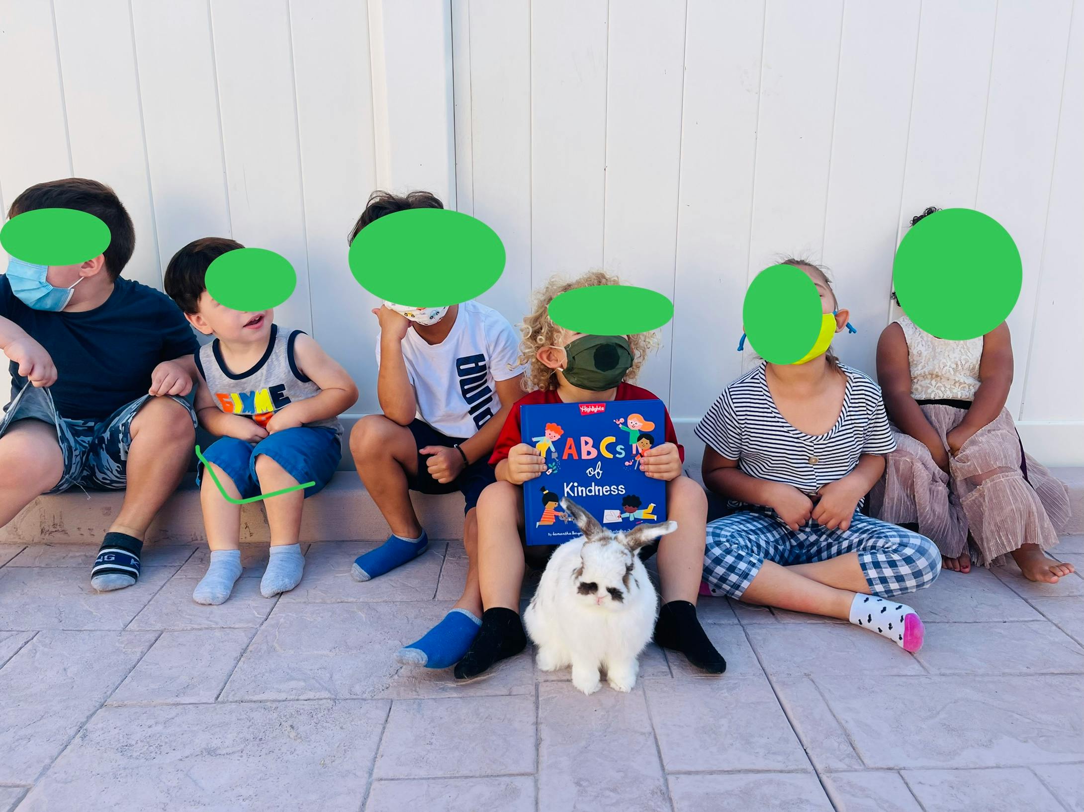 Children sitting with a rabbit and a book titled "ABC of Kindness"