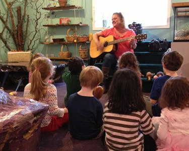 Person playing guitar for a group of children