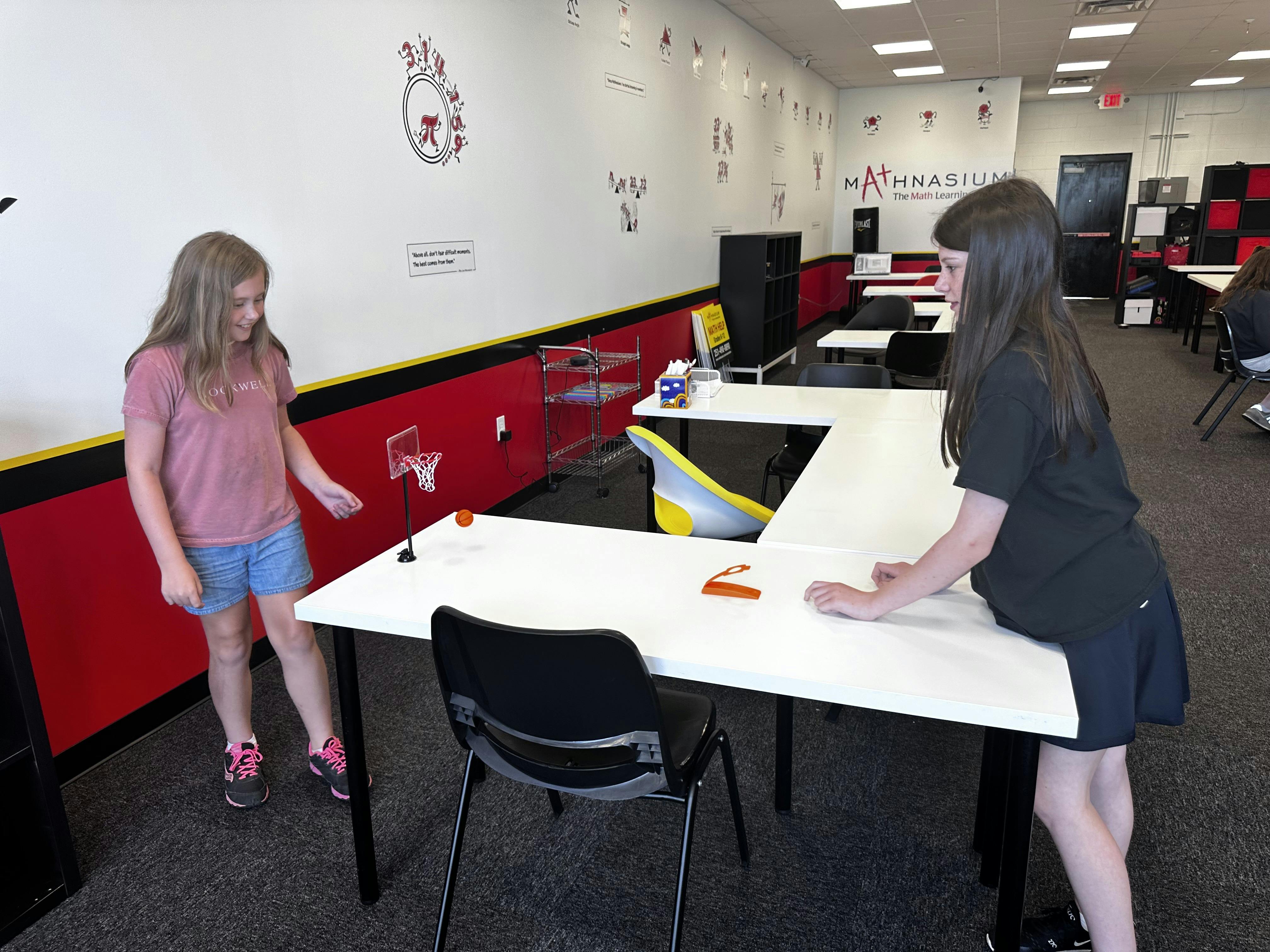 Two children standing at a table in a classroom