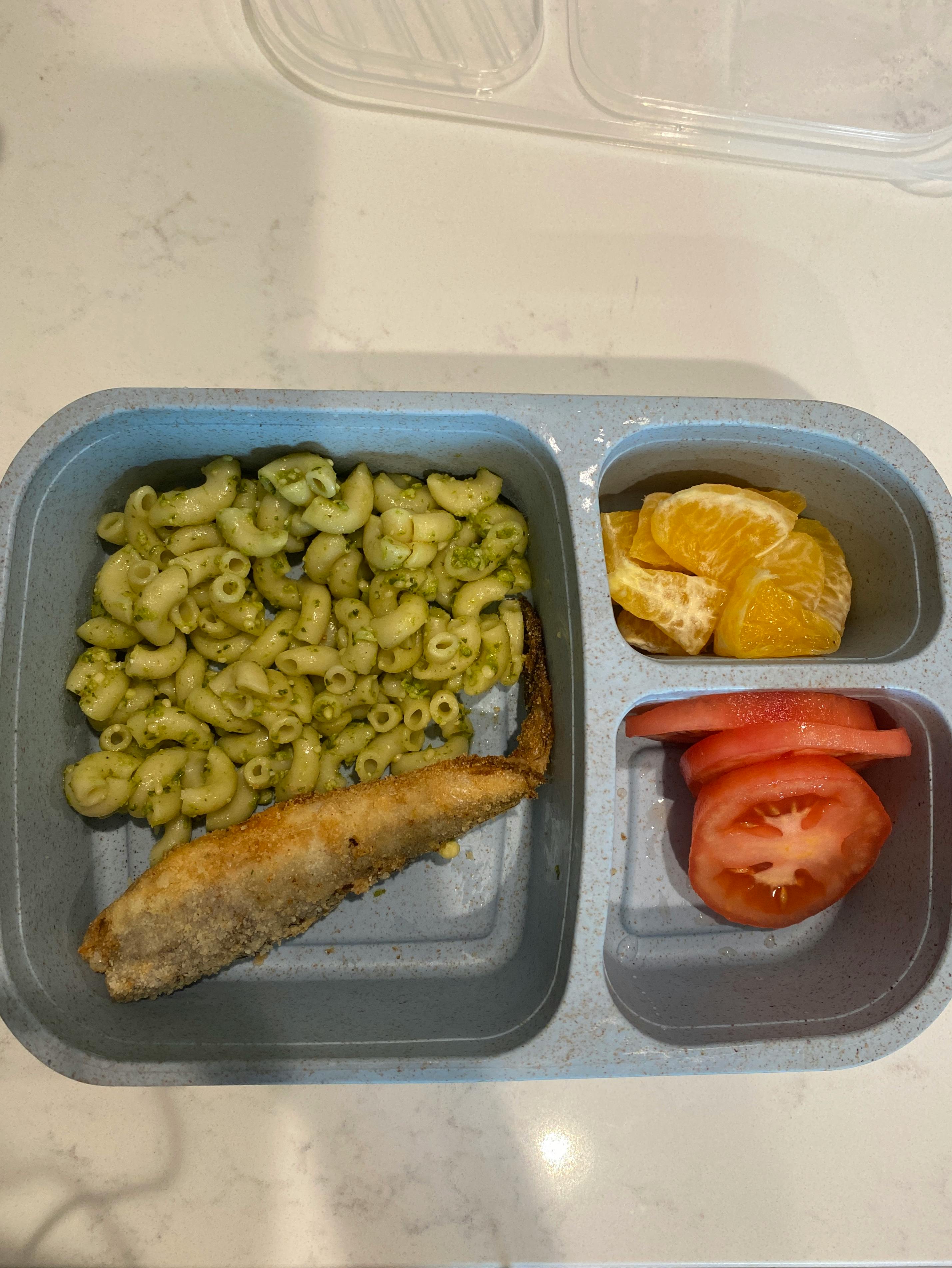 Lunchbox with pasta, fish, orange slices, and tomato slices